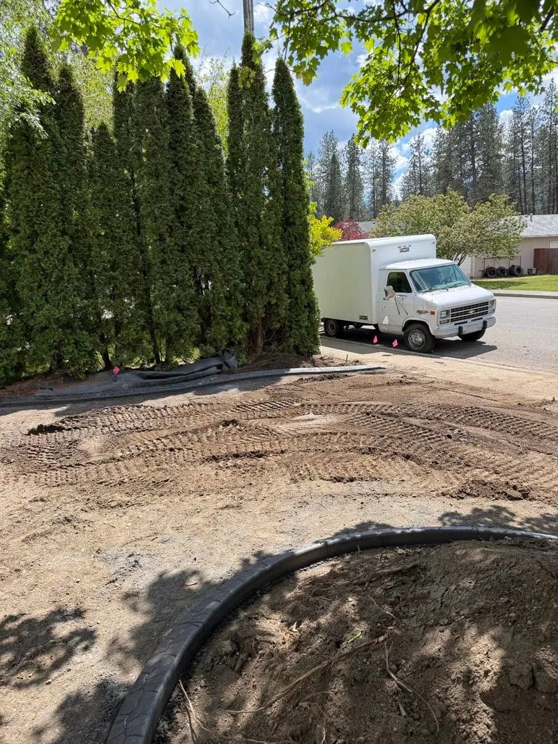 Graded yard with new curbing and a work van parked at the street