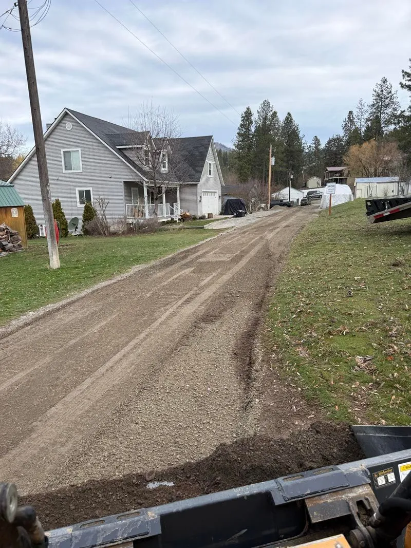 Freshly graded rural gravel road leading past a house