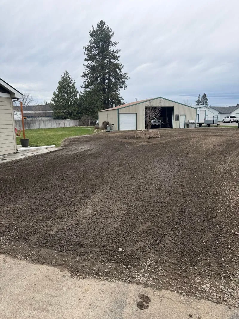 Wide graded dirt driveway in front of a shop building