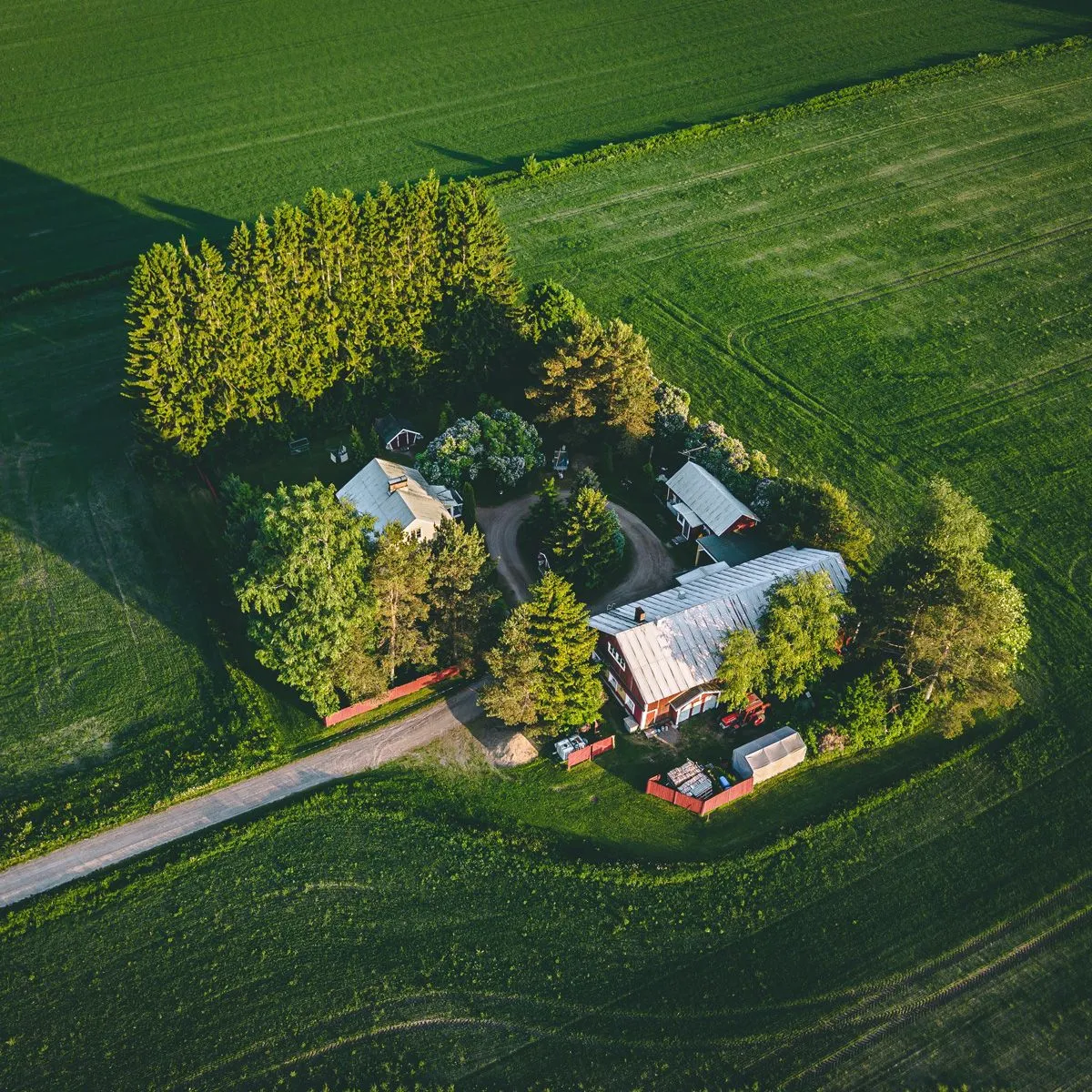 Aerial view of green farmland around a red barn and farmhouse