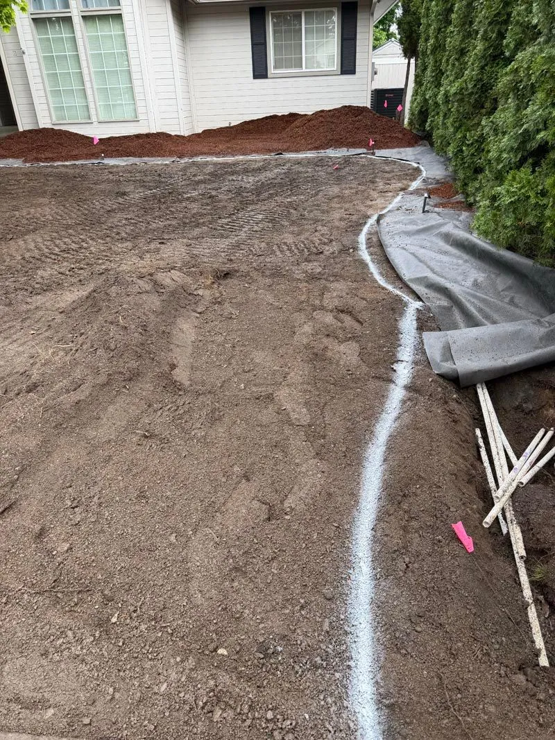 Curbing form and irrigation line laid along a prepared yard edge